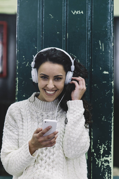 fröhliches Mädchen lächelnd hört er Musik mit weißen Kopfhörern - Foto, Bild