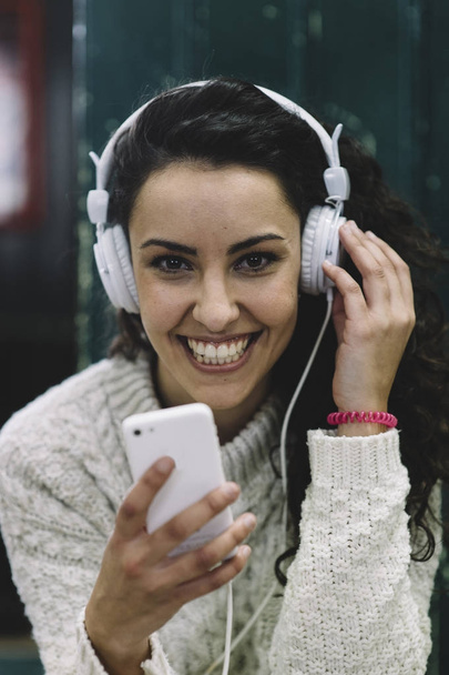 Gelukkig meisje lacht hij luistert naar muziek met witte koptelefoon - Foto, afbeelding