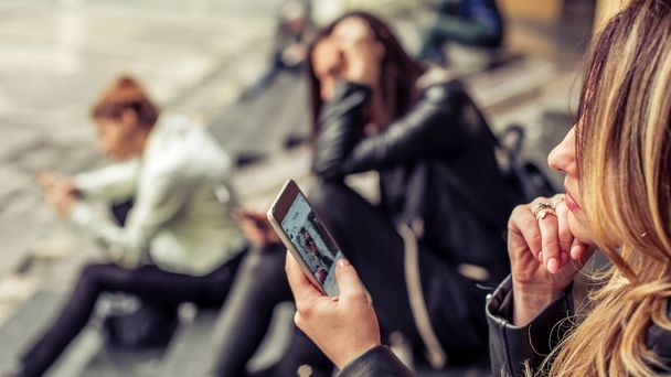 Group of girls sitting on the city stairs with smartphone - Valokuva, kuva