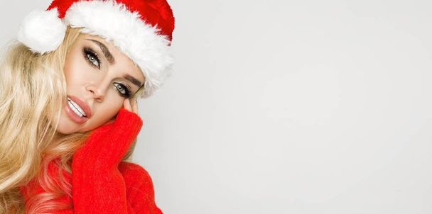 Όμορφη σέξι ξανθιά γυναίκα μοντέλο ντυμένος με ένα καπέλο Santa Claus. Αισθησιακό κορίτσι για τα Χριστούγεννα. - Φωτογραφία, εικόνα