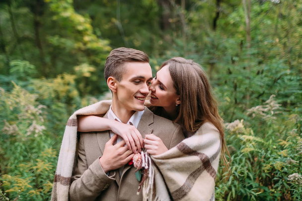 Couple under the plaid in an autumn romantic forest. Autumn wedding outdoors. - Foto, afbeelding