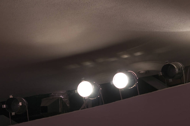 Δύο φωτεινά προβολείς που λάμπουν κάτω από το ανώτατο όριο στο Μέγαρο Μουσικής. - Φωτογραφία, εικόνα