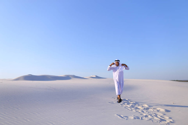 Happy Arab mies kävelee keskellä valkoista autiomaata ja nauttii elämästä o
 - Valokuva, kuva