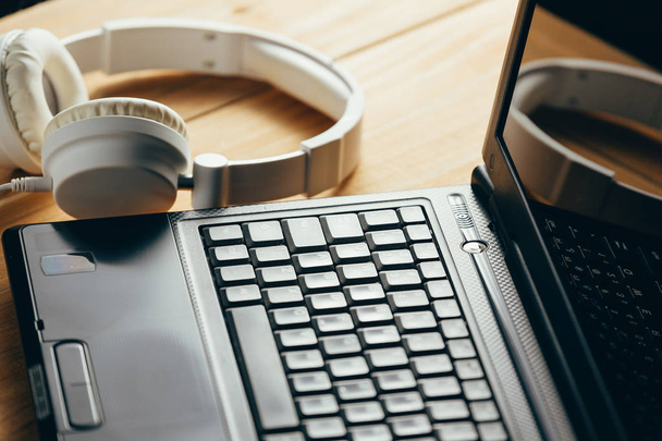 Headphones and laptop on wooden desk table. Music concept. - Photo, image