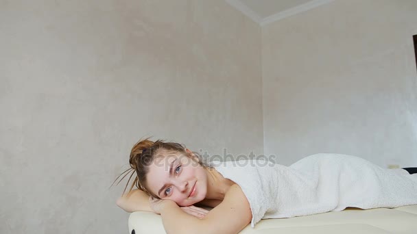 Dziewczyna relaksuje po zabiegi kosmetyczne i patrzy na aparat, leżąc na kanapie w gabinecie lekarskim jasne. - Materiał filmowy, wideo