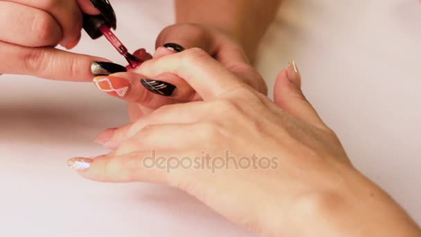 En la mano femenina izquierda, la manicura en el salón de belleza utiliza un barniz rojo en el dedo índice
. - Metraje, vídeo