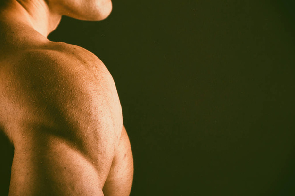 Muscular, relief bodybuilder on a black background - Foto, afbeelding