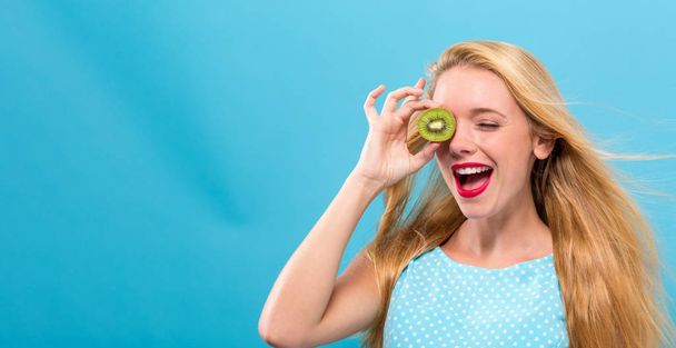 Happy young woman holding kiwis - Foto, afbeelding
