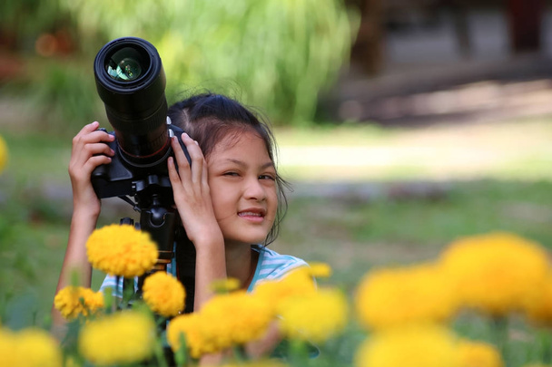 Lapset ottavat kuvan keltaisesta kukasta dslr-kameralla puutarhassa
 - Valokuva, kuva