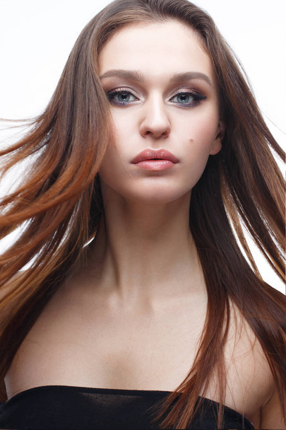 A young girl with a gentle classical makeup and loose hair. Beautiful model with nude makeup and straight hair. Beauty of face and shining skin - Zdjęcie, obraz