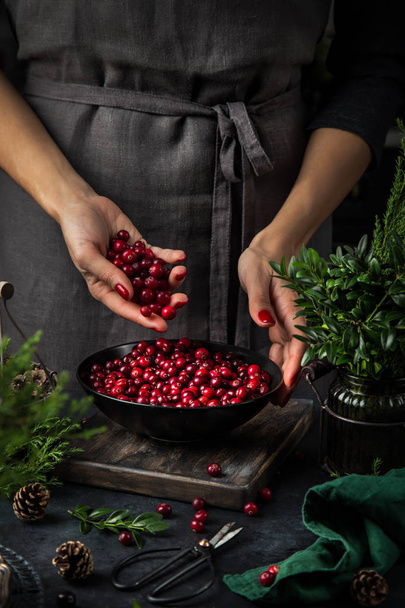 fresh cranberry in woman hands. Dark kitchen table - Photo, Image
