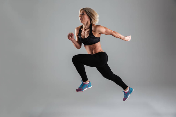 Full length portrait of a strong muscular adult woman jumping - Fotó, kép