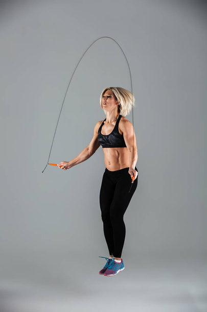 Full length portrait of a muscular adult sportswoman jumping - Valokuva, kuva