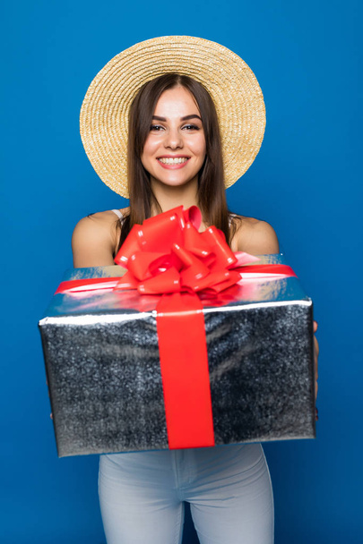 Smiling woman present gift box with red ribbon. Beauty woman isolated on blue studio background - Foto, Bild