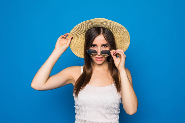 Lächelnde Schönheit junge Frau mit Sonnenbrille und Hut in einem modernen Stil auf dem Hintergrund einer blauen Wand. - Foto, Bild