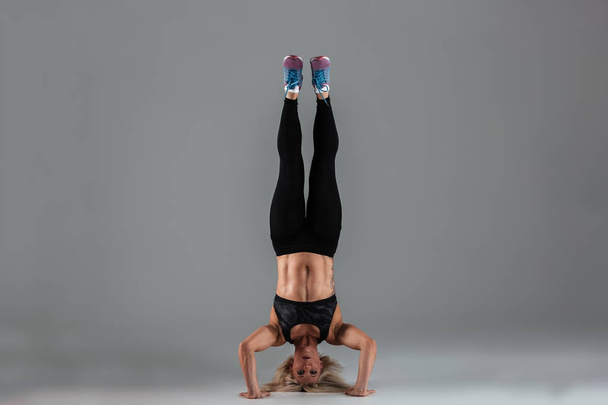 Full length portrait of a muscular sportswoman standing upside down - 写真・画像