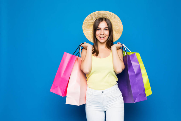 красивая женщина в шляпе в стильной одежде, шоппинг распродается на синем фоне, разноцветные сумки стоят на полу. Чёрная пятница
. - Фото, изображение