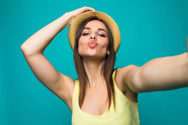 Portret van een lachende leuke vrouw selfie foto verzenden kussen op smartphone geïsoleerd op een gekleurde achtergrond maken - Foto, afbeelding