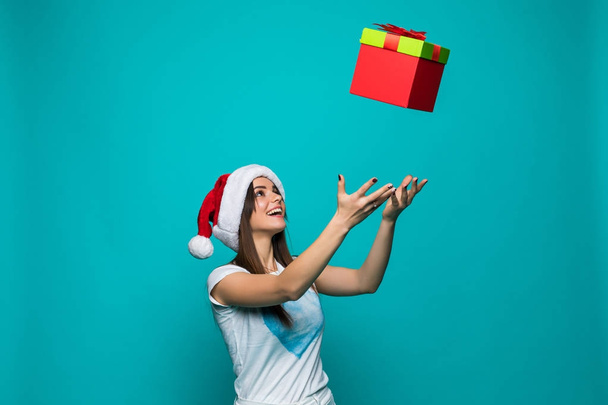 サンタ帽子の美容きれいな女性を背景色に分離されたクリスマス プレゼント彼女の手でキャッチします。 - 写真・画像