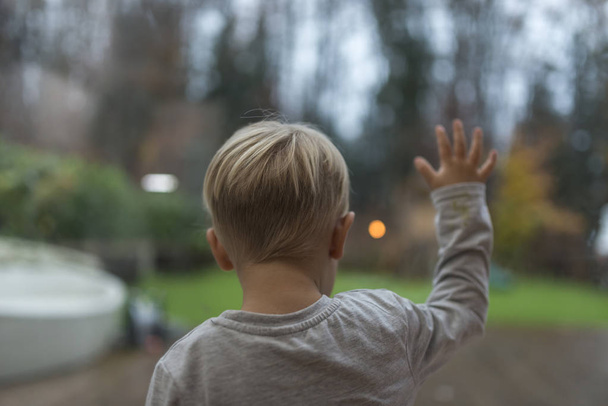 Little boy standing staring out of a window - Fotografie, Obrázek