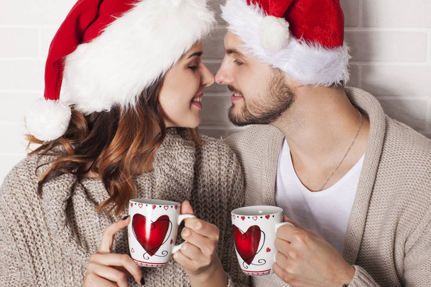 Lächelndes Paar mit Weihnachtsmütze und Weihnachtstasse. - Foto, Bild