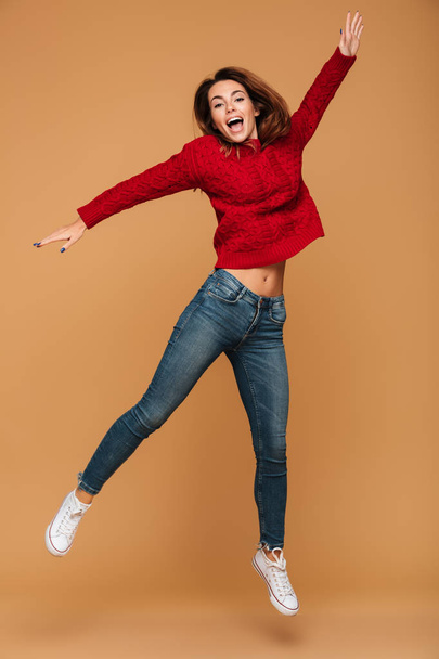 Smiling caucasian woman dressed in sweater jumping - Photo, image