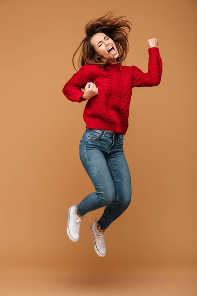 Screaming caucasian woman dressed in sweater jumping - Φωτογραφία, εικόνα