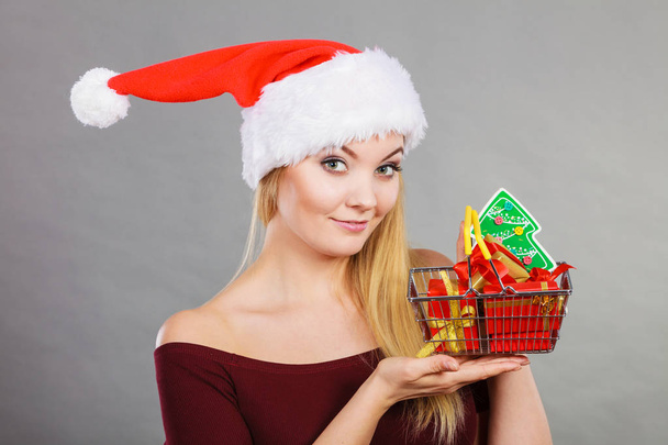 Santa woman holding shopping cart with christmas gifts - Foto, afbeelding