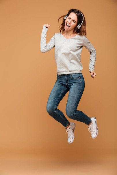 Full length photo of young attractive woman in headphones jumpin - Fotografie, Obrázek