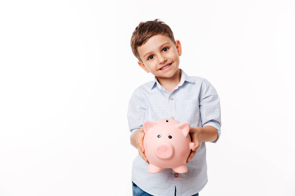 Portrait of a smiling cute little kid holding piggy bank - Fotó, kép