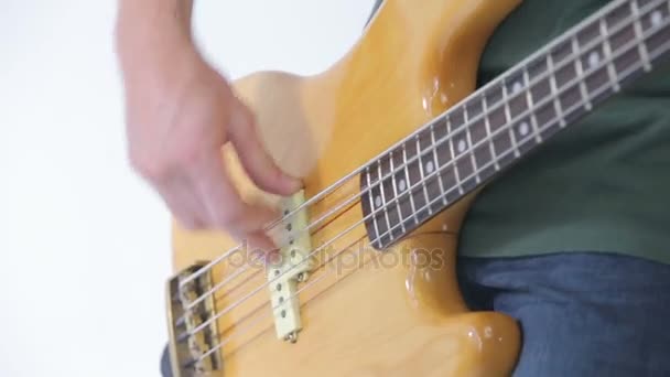Bass guitar player fingers on the strings close-up isolated on white - Кадры, видео