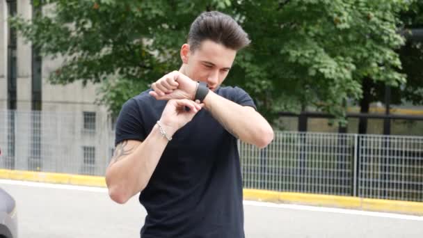 Young man using smartwatch outside - Felvétel, videó