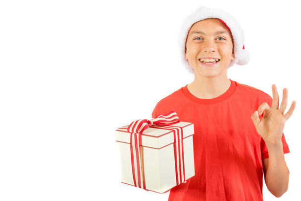 Young teenage boy wearing a Santa Christmas hat with a gift - Photo, image