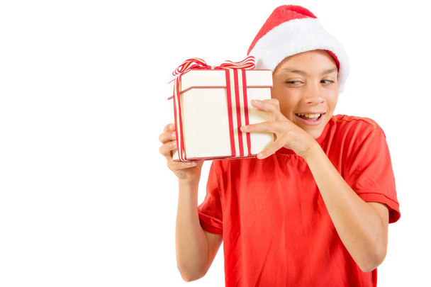 Young teenage boy wearing a Santa Christmas hat with a gift - Photo, image