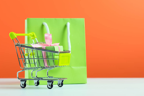 Green gift box in shopping cart and bag - Photo, Image
