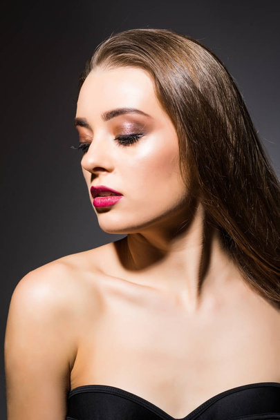 Beautiful woman with professional make up on dark background - Фото, изображение