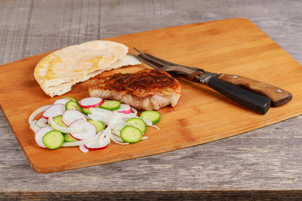 Pork steak met radijs en UI komkommers - Foto, afbeelding