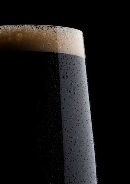 Copo frio de cerveja escura com espuma e orvalho
 - Foto, Imagem