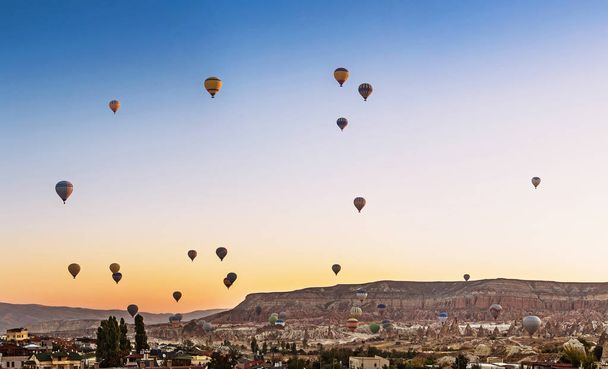 Many Hot air balloons flying over Goreme town in Cappadocia, panoramic view - Foto, Bild