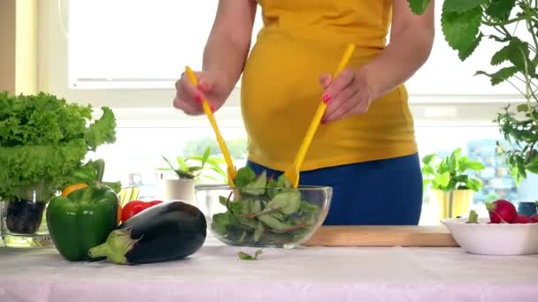 Těhotná dívka budoucí matka směšovací přírodní salát a pohladit dlaní její bříško - Záběry, video