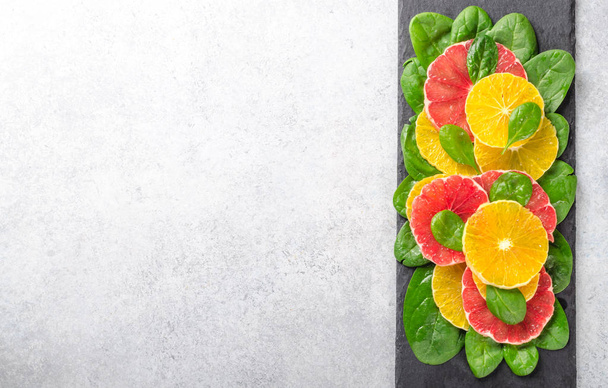 Ensalada hecha de rodajas de naranja y pomelo y hojas de espinaca en
 - Foto, imagen