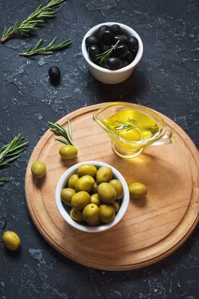 Black and green olives in wooden bowls on stone black background - Photo, Image
