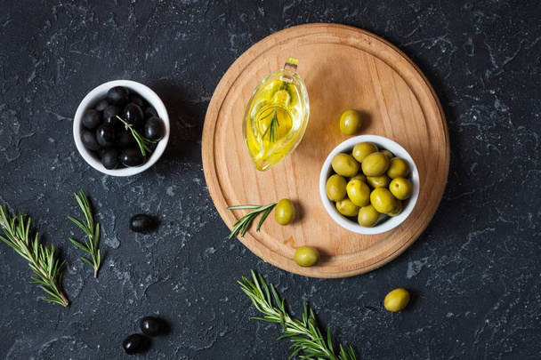 Black and green olives in wooden bowls on stone black background. - Fotoğraf, Görsel