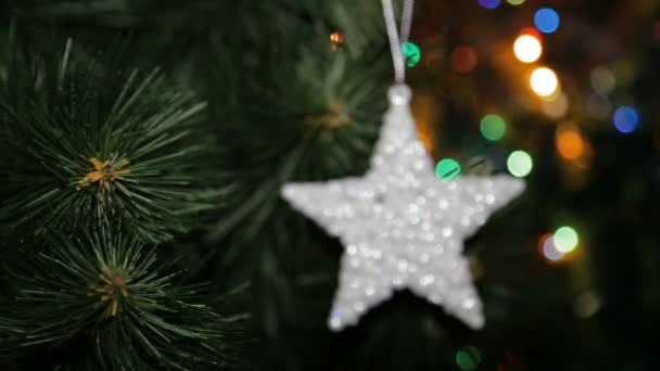 Χριστουγεννιάτικο παιχνίδι σε ένα χριστουγεννιάτικο δέντρο ενάντια σε μια γιρλάντα στη θολούρα - Πλάνα, βίντεο