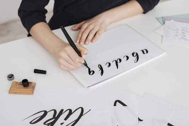 Close up photo of young woman hands writing alphabet on paper on desk  isolated - Фото, изображение
