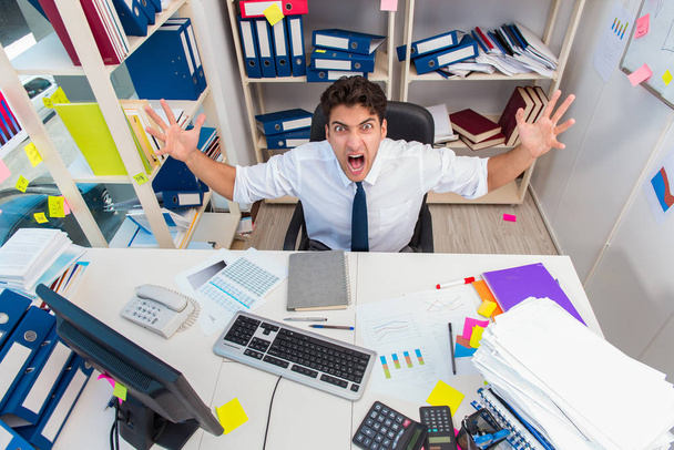 Businessman working in the office with piles of books and papers - Photo, Image