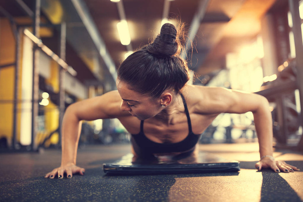 Woman in gym putting arms in proper position for pushups exercise - Fotoğraf, Görsel