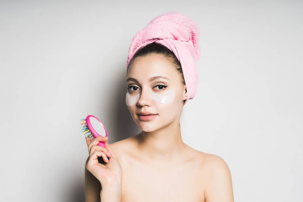 surprised young girl with clean skin, pink towel on her head, silicone patches under eyes looking at camera, smiling - Foto, Imagen