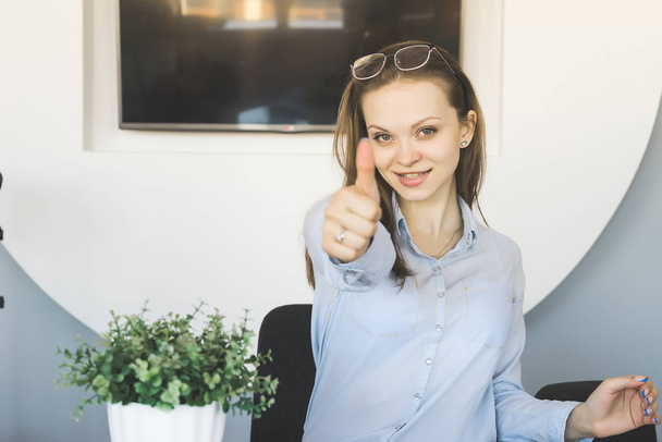 successful young woman working in the office, smiling, showing thumb up - Valokuva, kuva