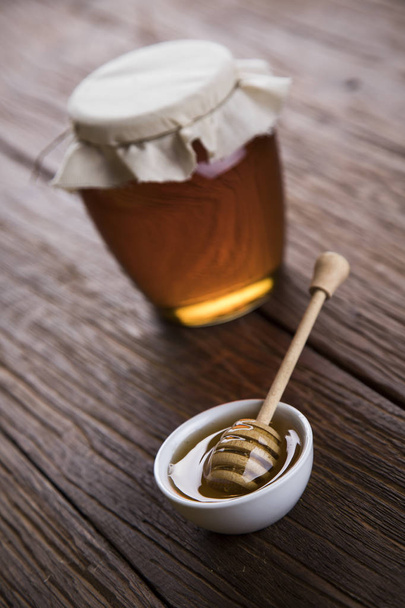 Honingpot met dipper en stromende honing  - Foto, afbeelding